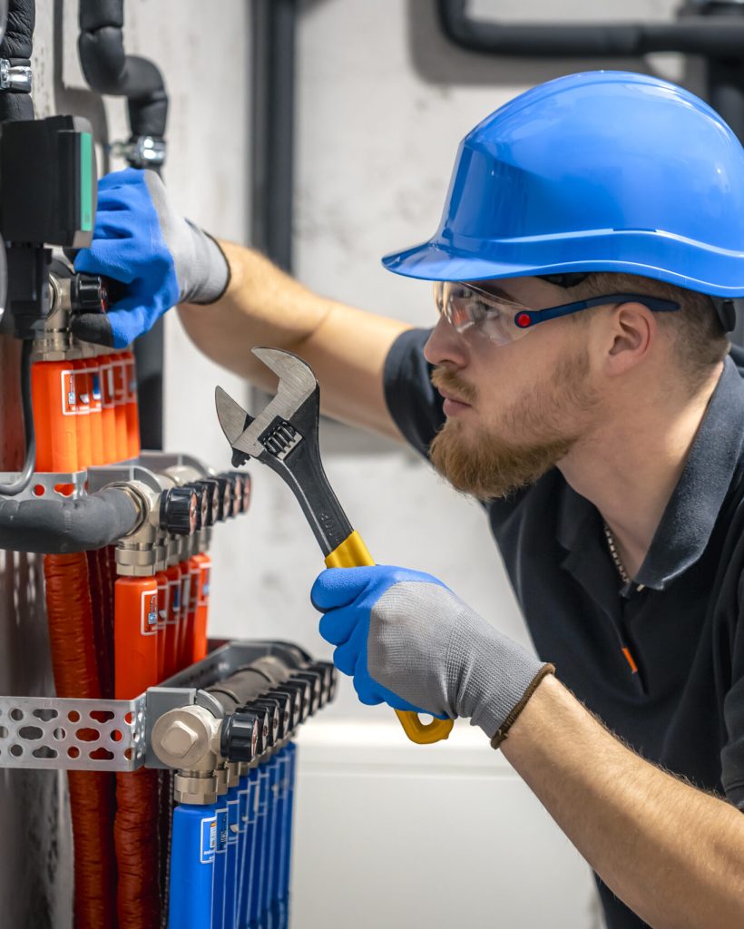 The technician checking the heating system in the boiler room. Adjusting heating valves in a residential building. A plumbing and heating technician works.